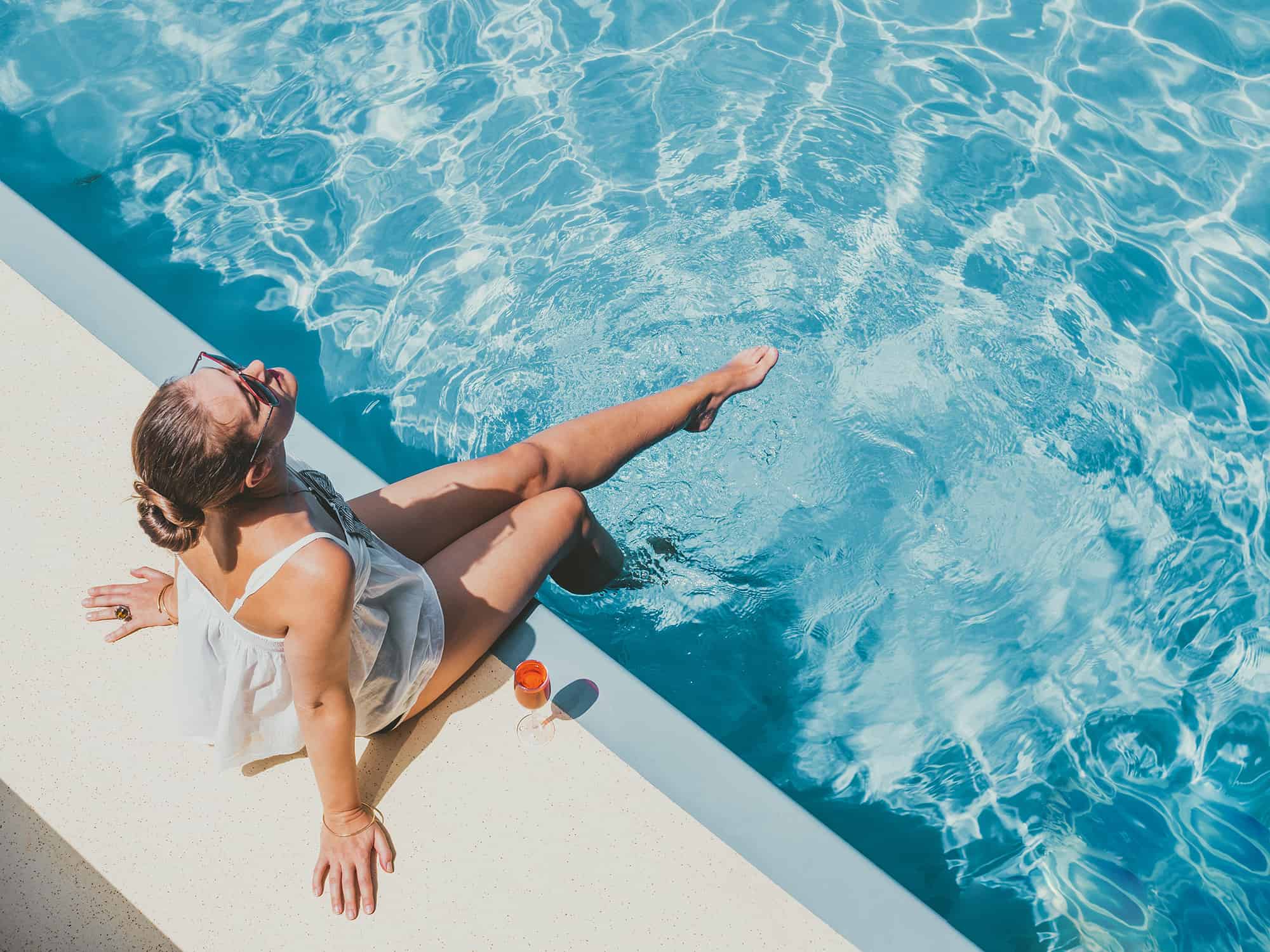 Fashionable woman sitting by the pool on the empty deck